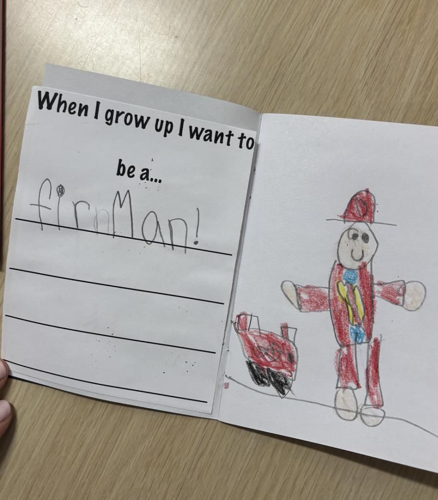 A child's drawing in a booklet showing a firefighter and a fire truck, with text stating "I want to be a fireman!"