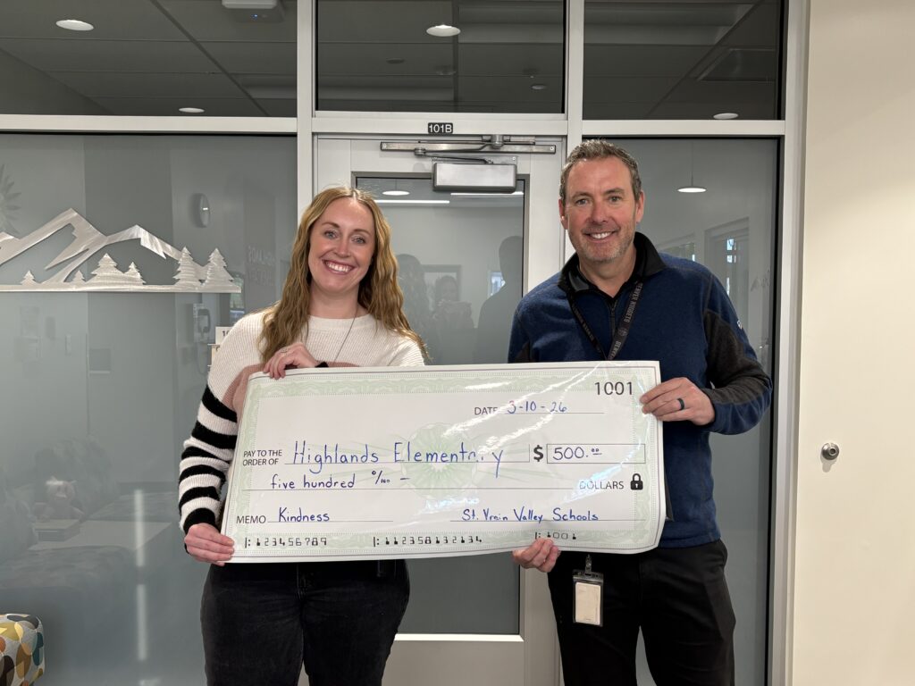 A woman and a man hold a large check for $500 made out to Highlands Elementary for "Kindness."